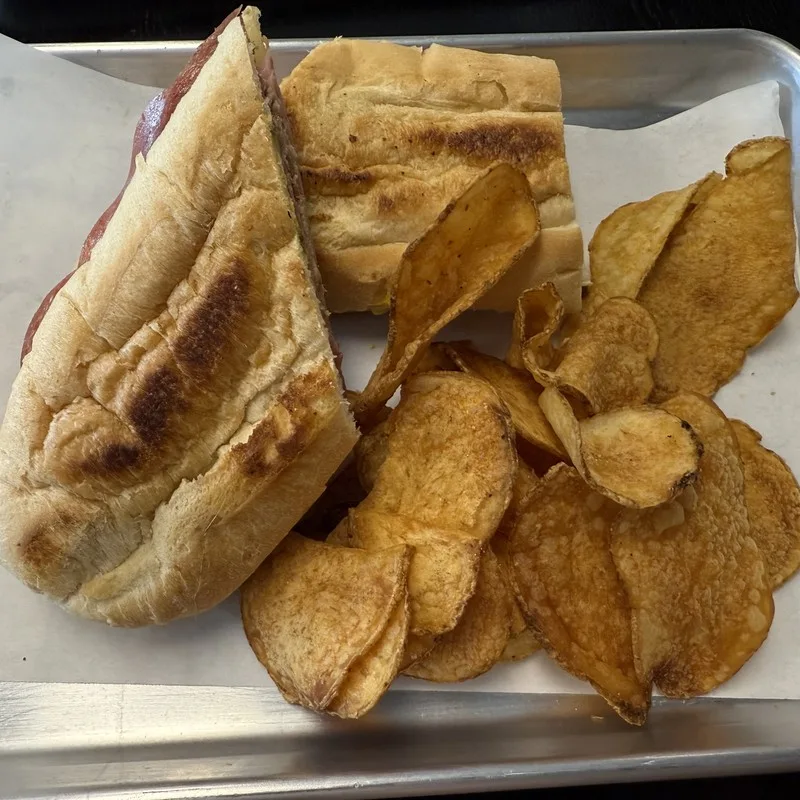 Muffaletta sandwich sliced in half with house-cut chips